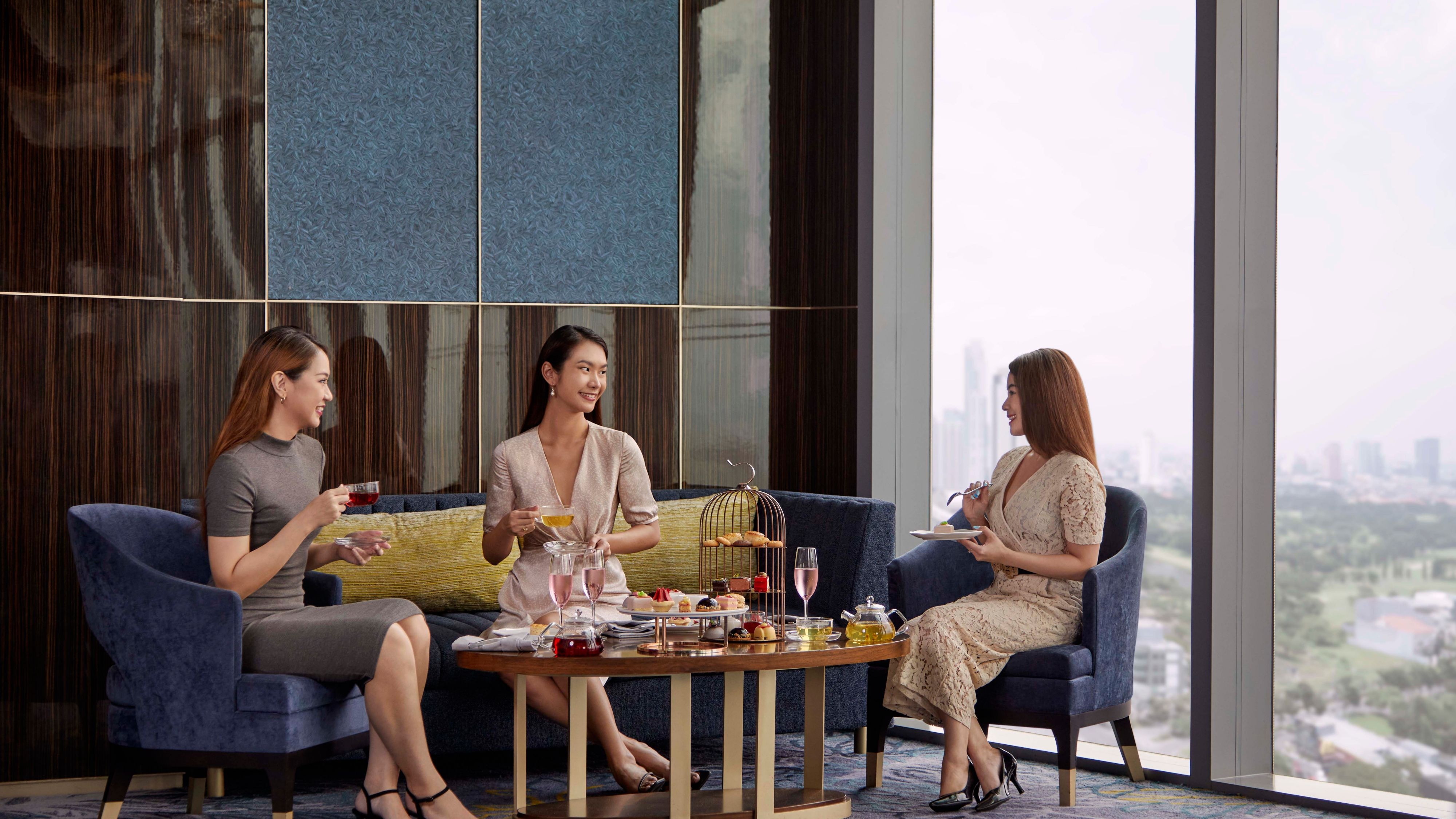 Tiga perempuan menikmati snack sore di salah satu restoran hotel